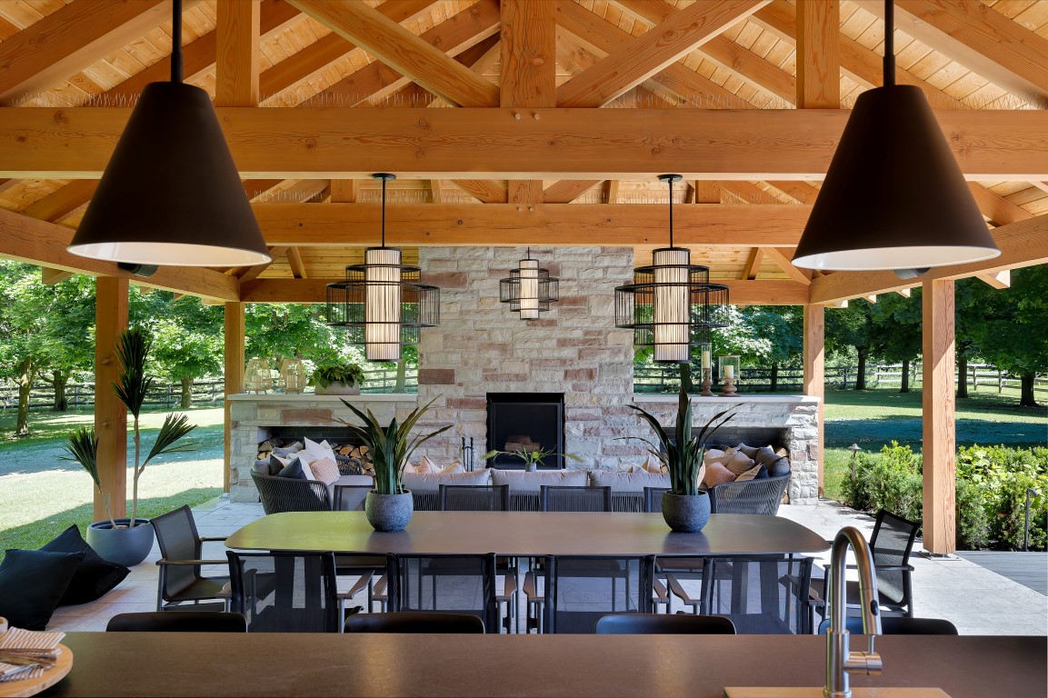 Farmhouse patio with a long table, chairs, and fireplaces.